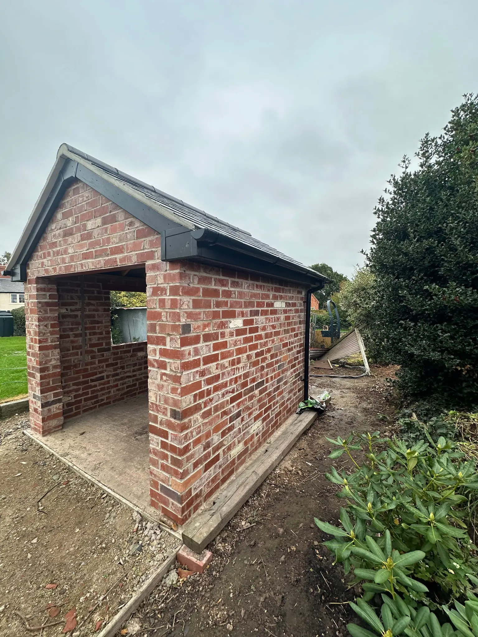 Side brick elevation of a garden outbuilding before surface cleaning