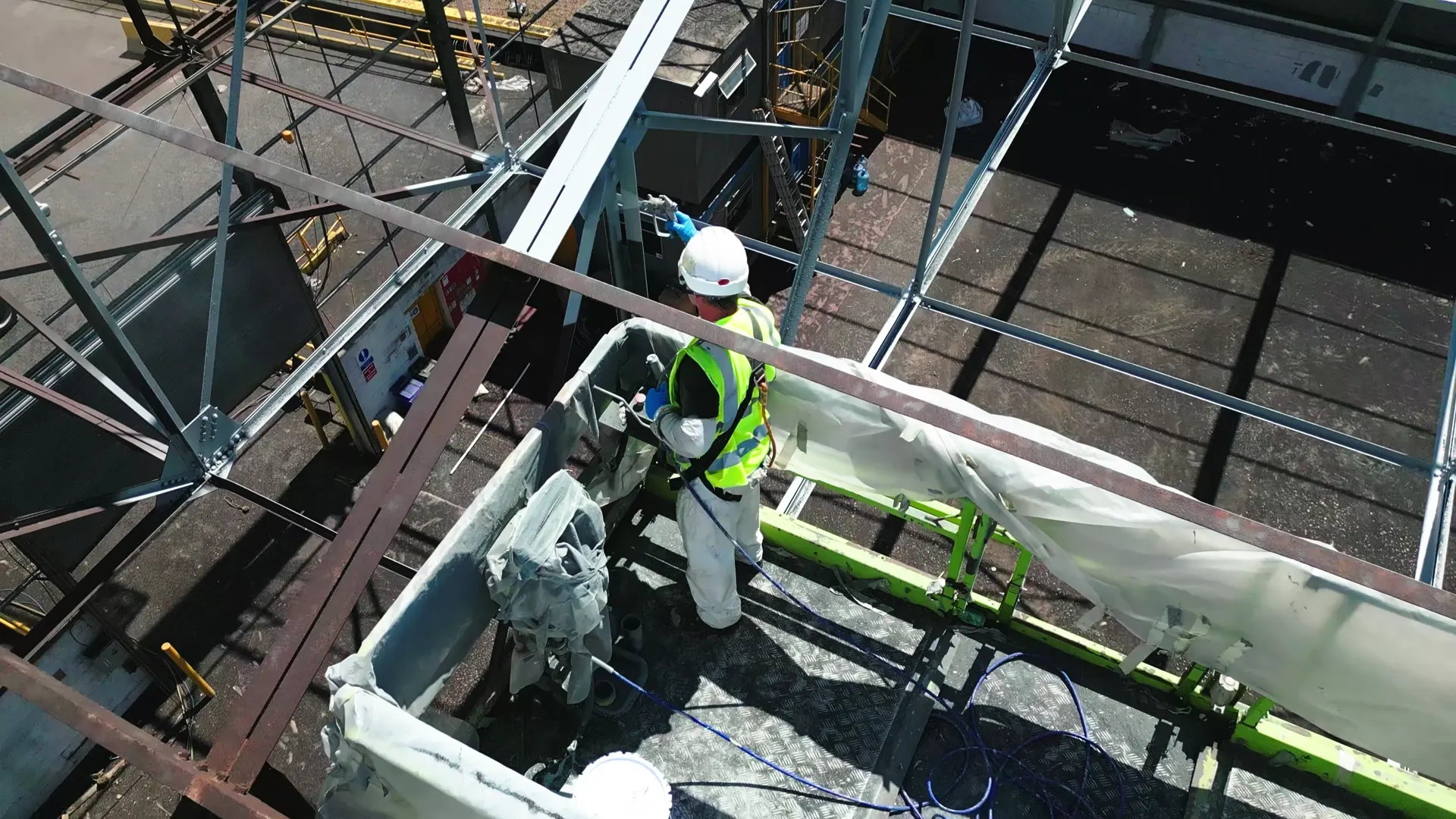 Operator applying a protective coating from a raised work platform