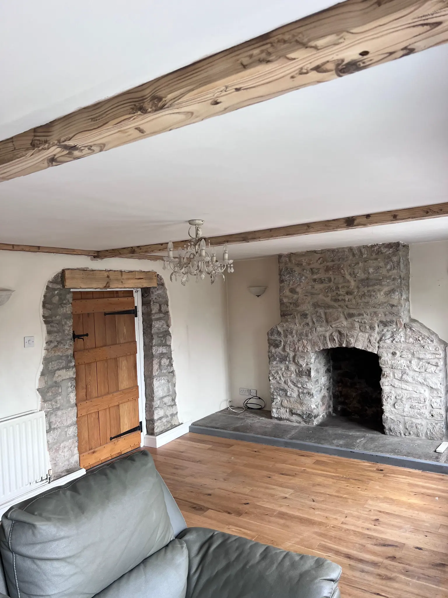 Lighter exposed beams above a stone fireplace after restoration