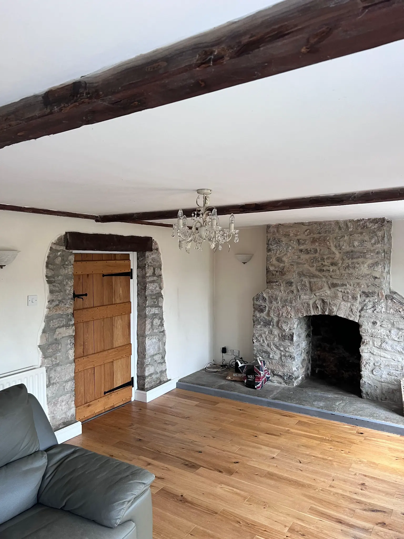 Dark finished beams above a stone fireplace before restoration