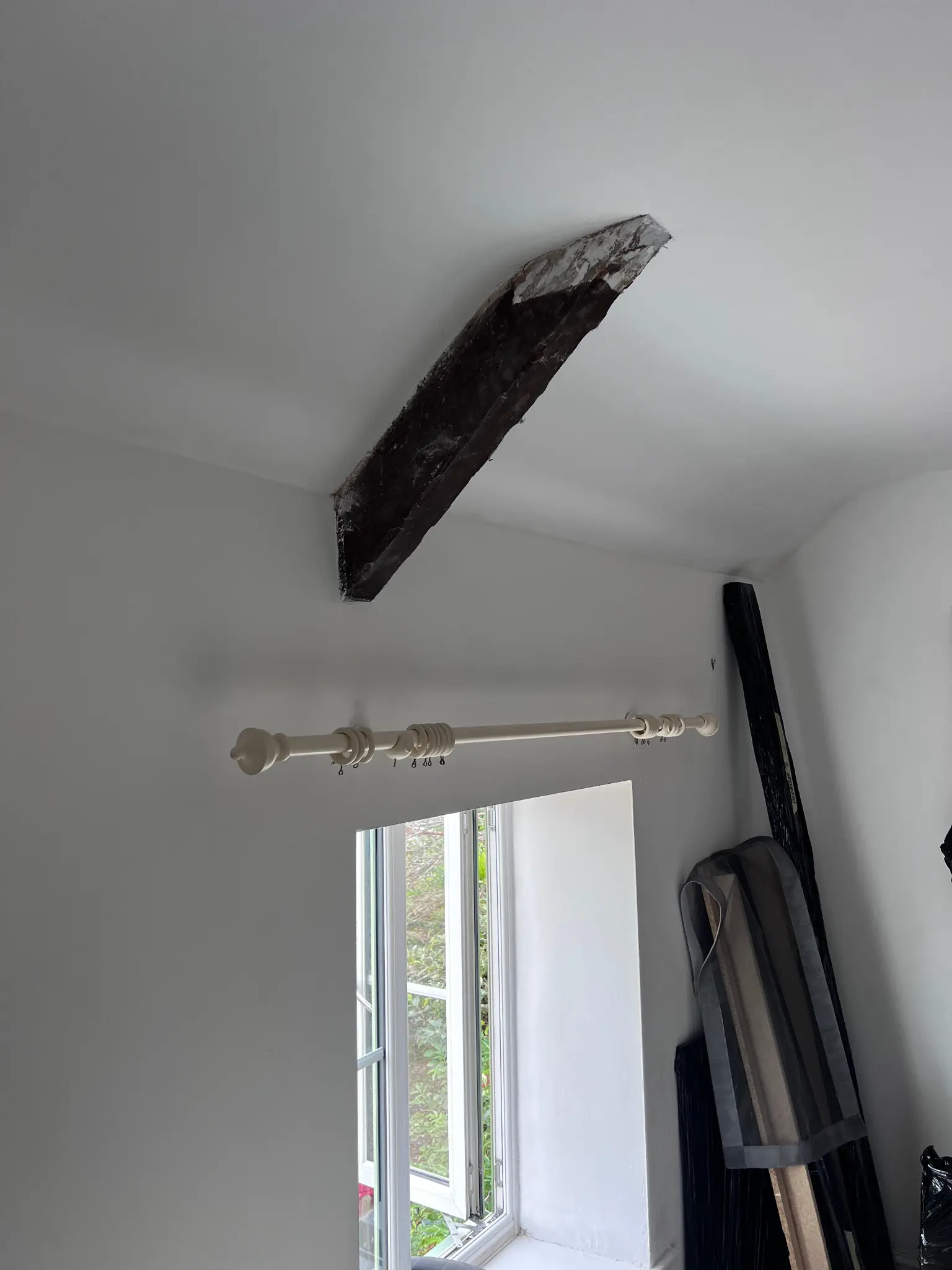 Dark finished ceiling beam above a window before restoration